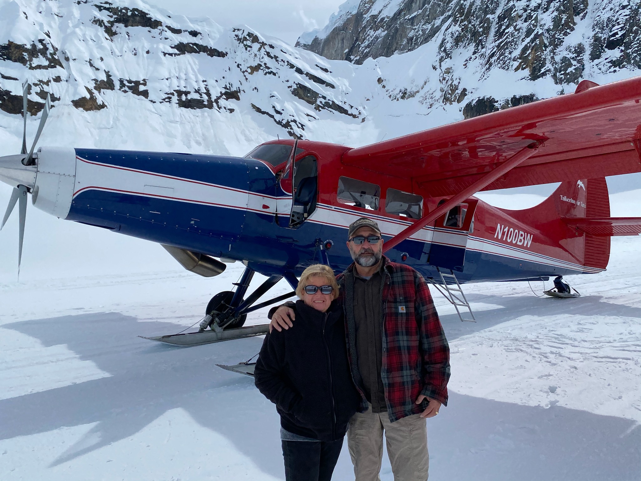the owners standing in snow in front of a plane